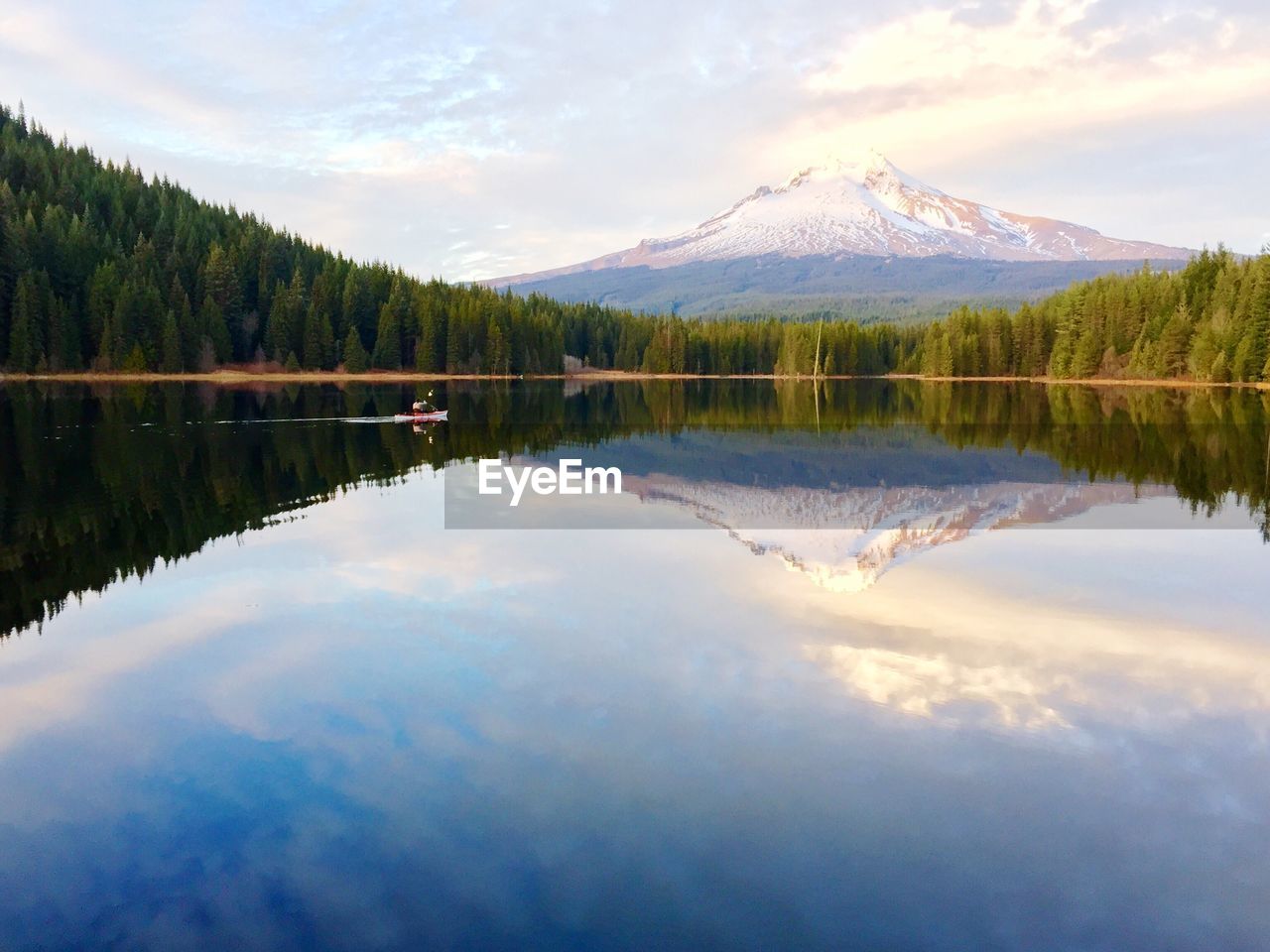 Scenic view of lake by trees with snowcapped mountain in background