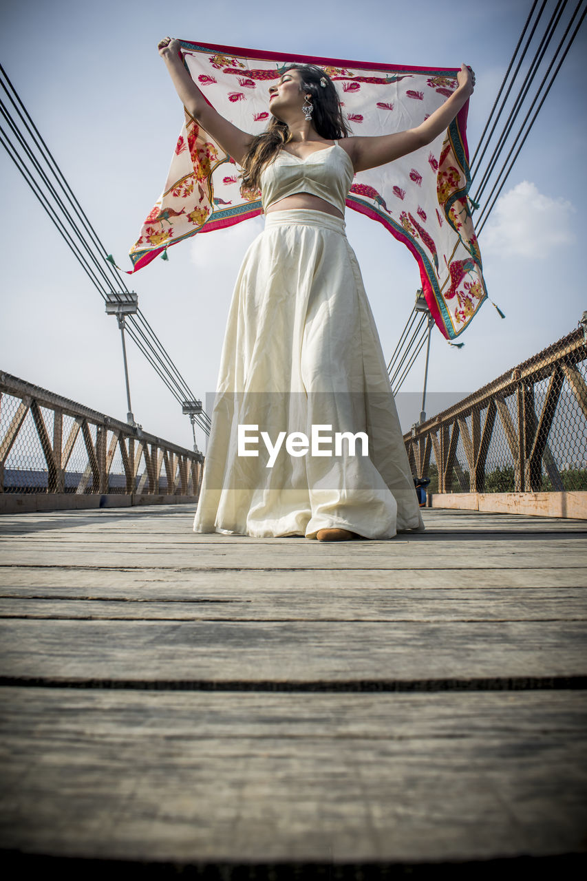 Low angle view of woman with bridge against sky