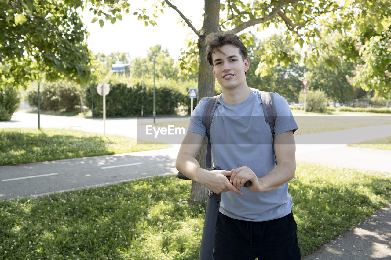 portrait of smiling young man standing against trees