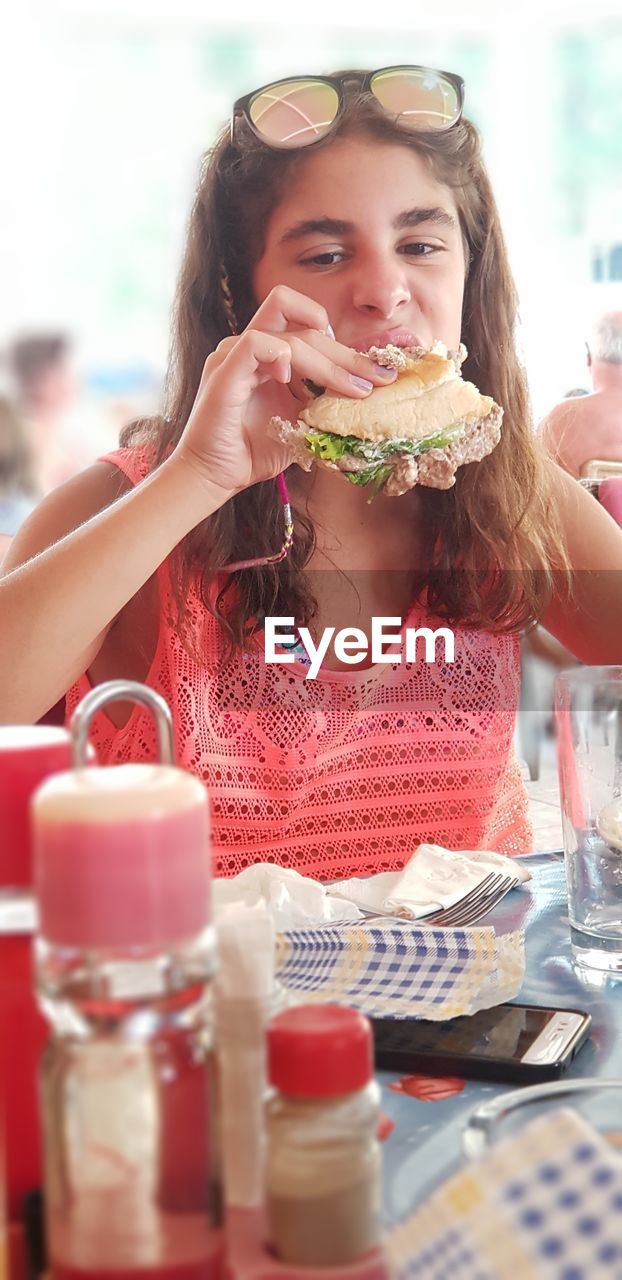 Girl looking away while eating food on table 