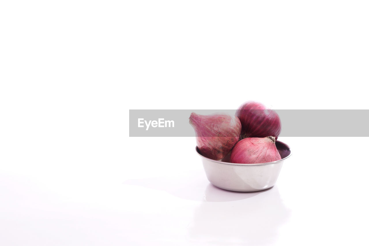 Close-up of onions in bowl over white background