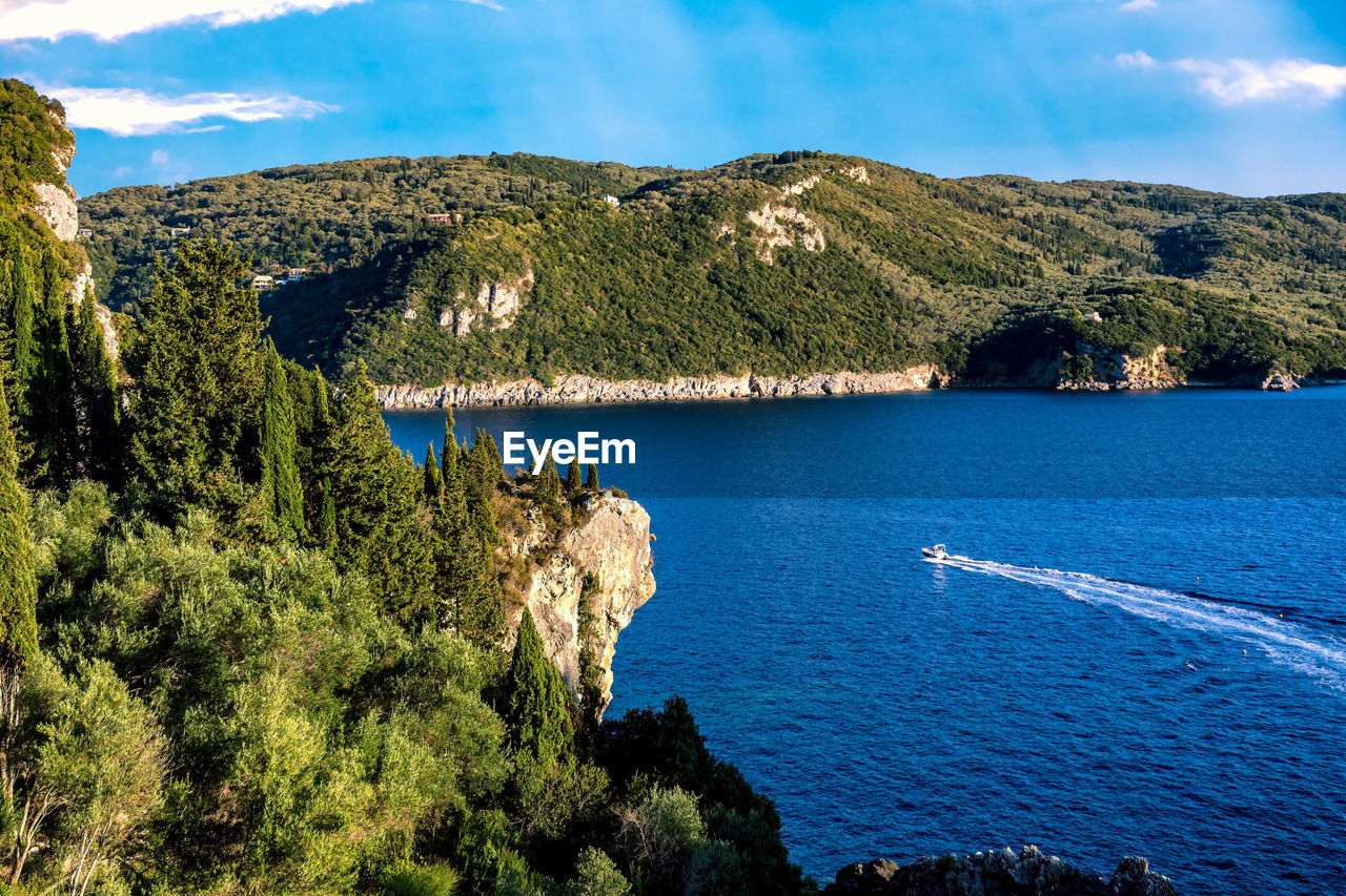 Scenic view of sea and mountains against sky in sunny day on corfu island.