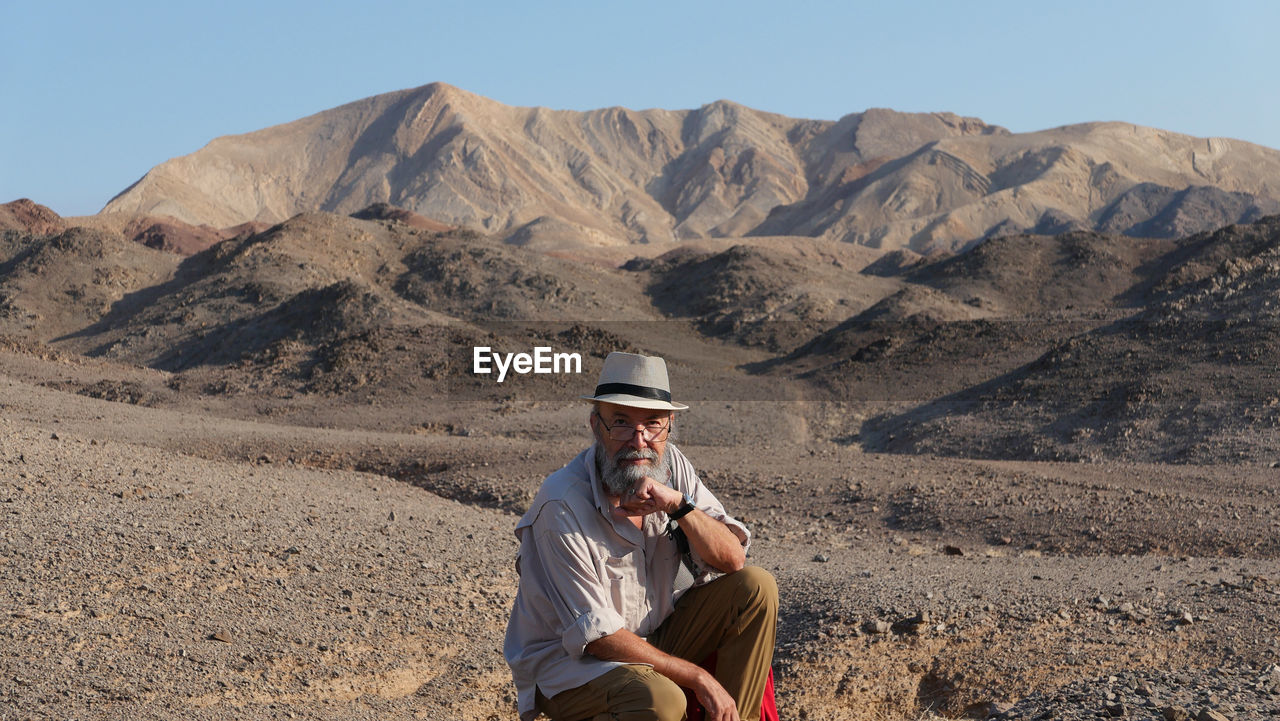 Senior man sitting on mountain in the desert 