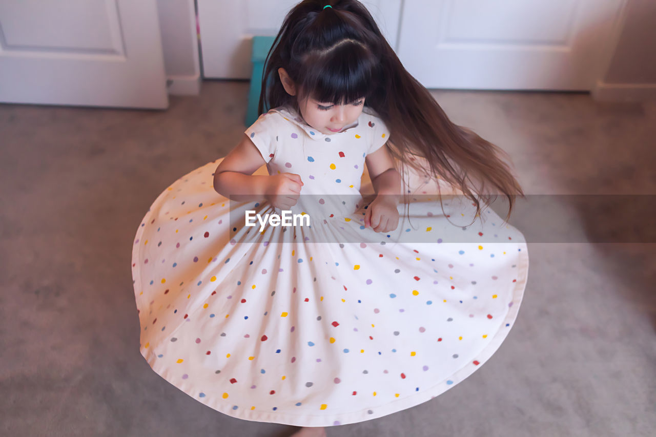 Preschool twirling in her bedroom, wearing a polka dot dress.