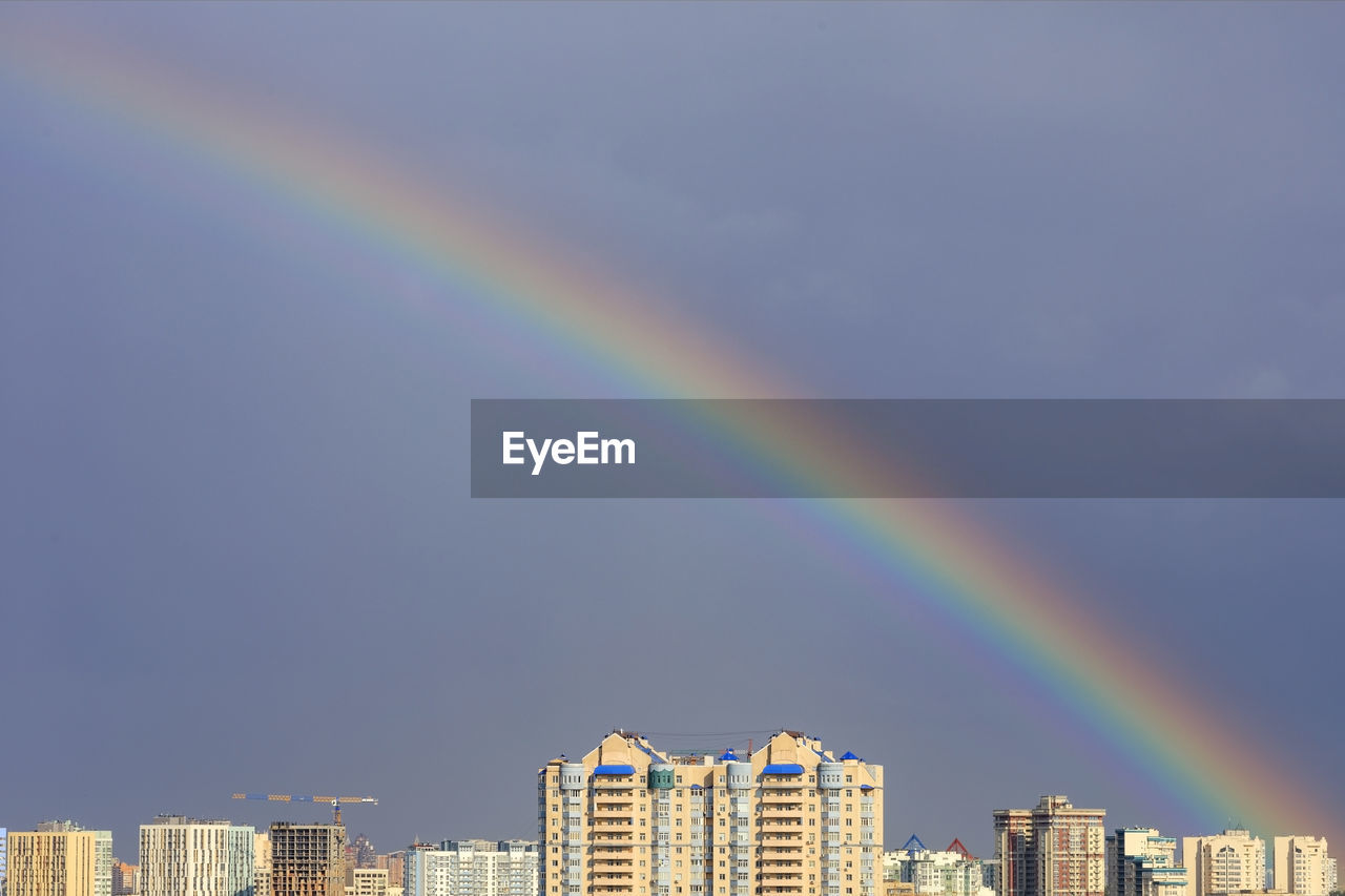 Low angle view of rainbow over buildings in city