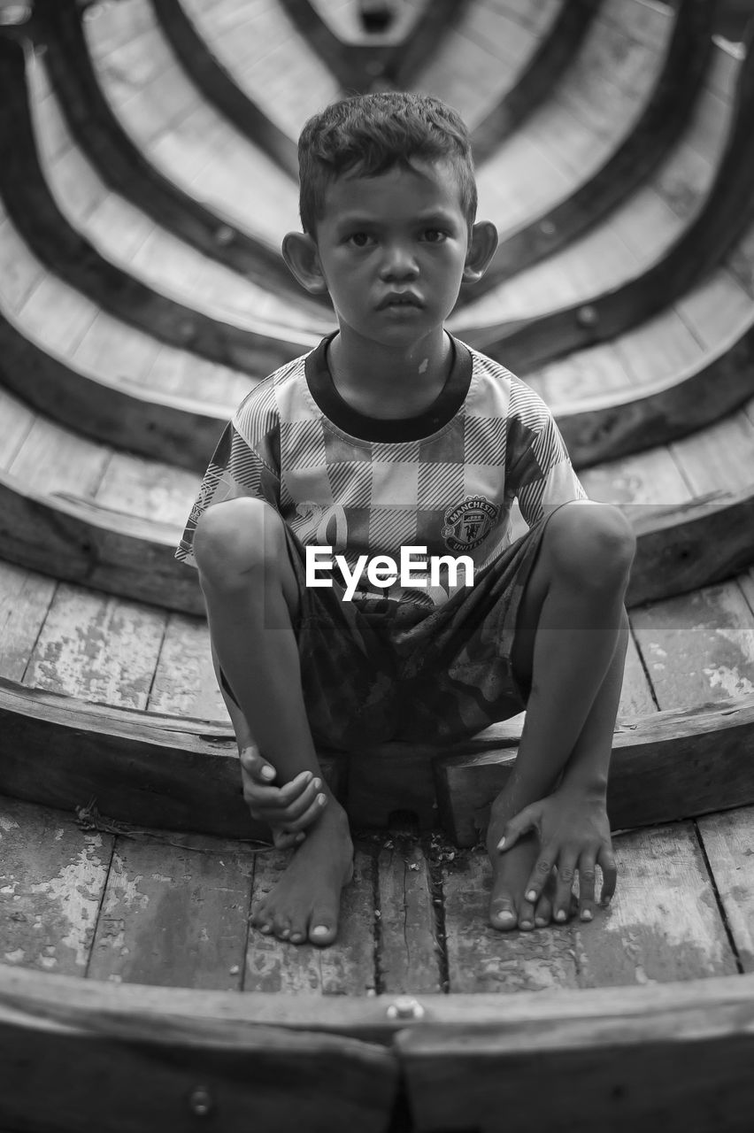 Portrait of boy sitting on built structure