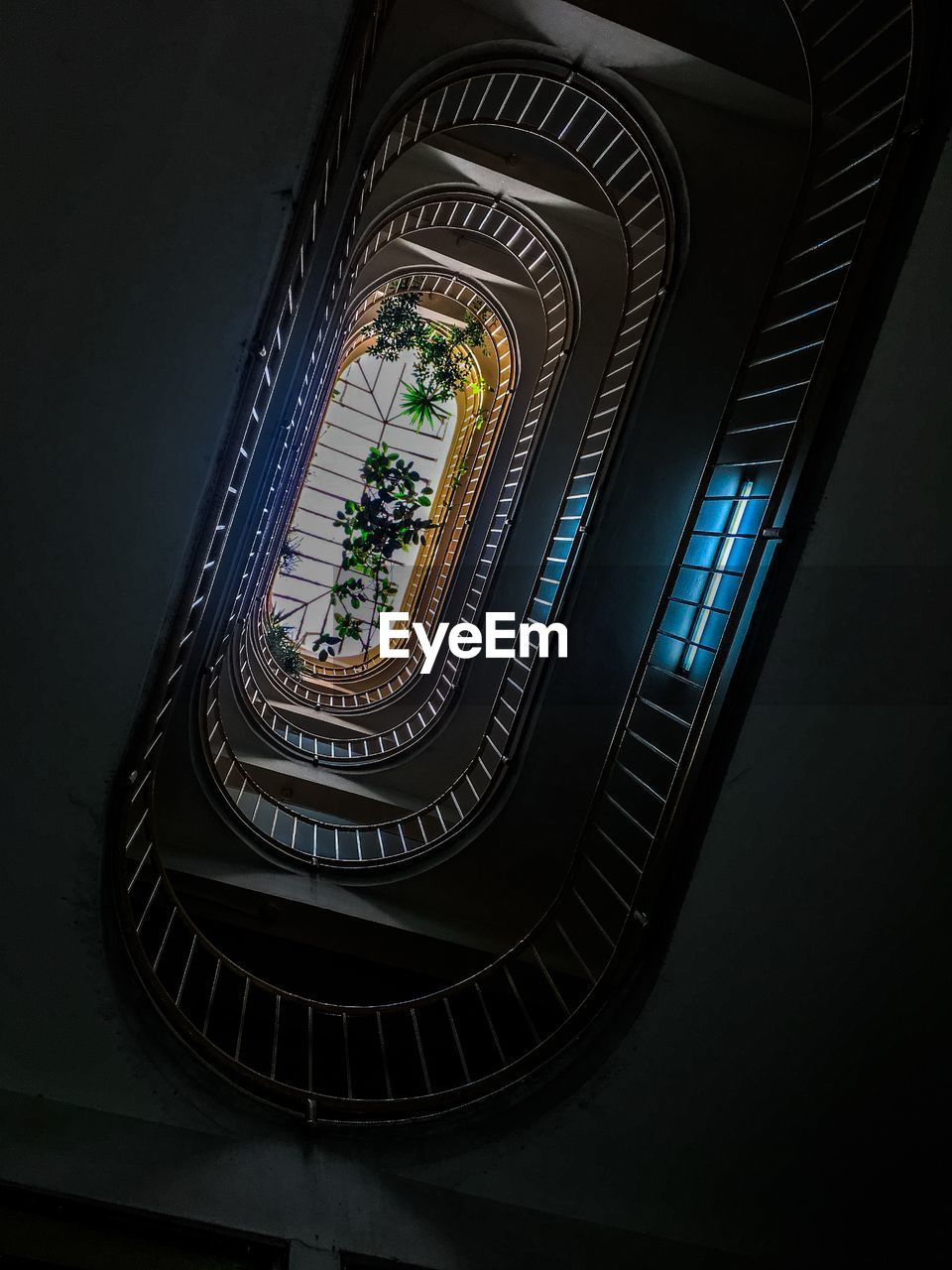 LOW ANGLE VIEW OF ILLUMINATED SPIRAL STAIRCASE IN BUILDING