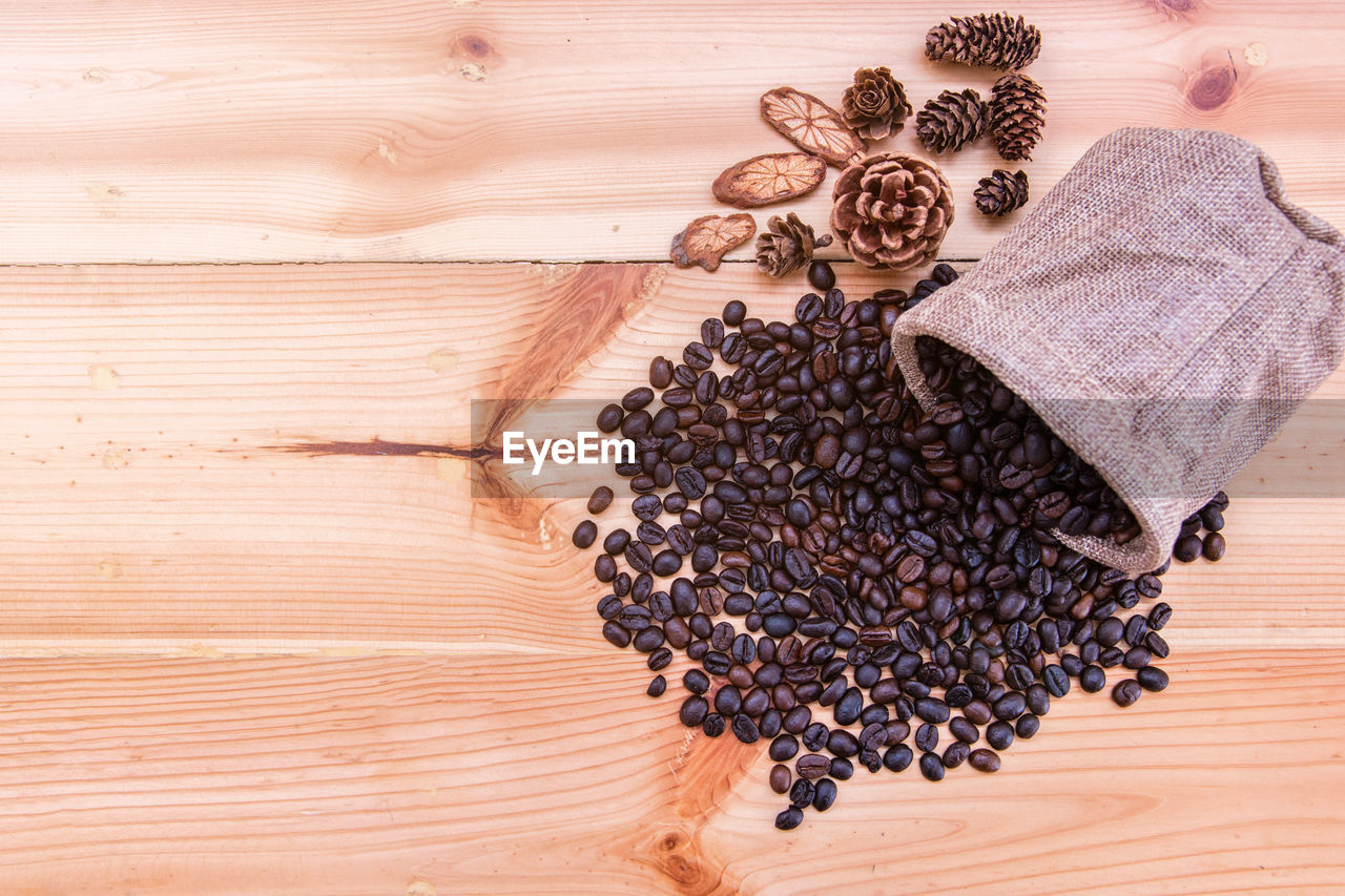 High angle view of roasted coffee beans with pine cones on wooden table