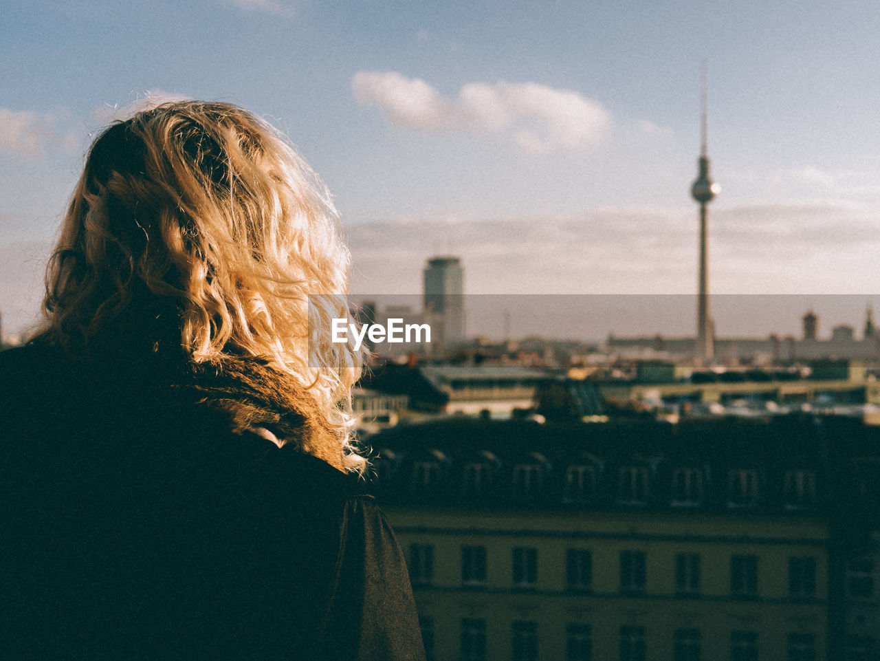 Rear view of woman standing in front of fernsehturm tower