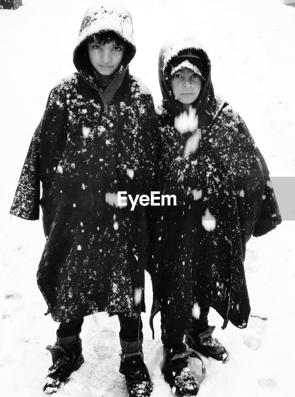 Full length portrait of siblings standing on snow covered field