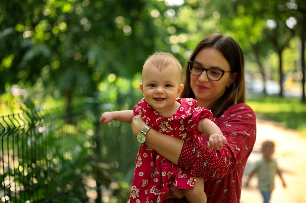 Mother holding her cute little baby girl in a park