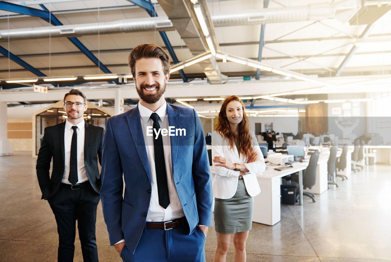 Portrait of happy businessman with colleagues in office