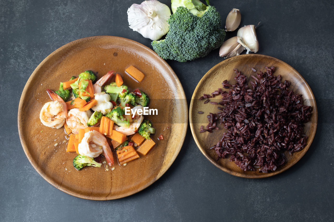 Broccoli stir fried with shrimp and rice on a black background