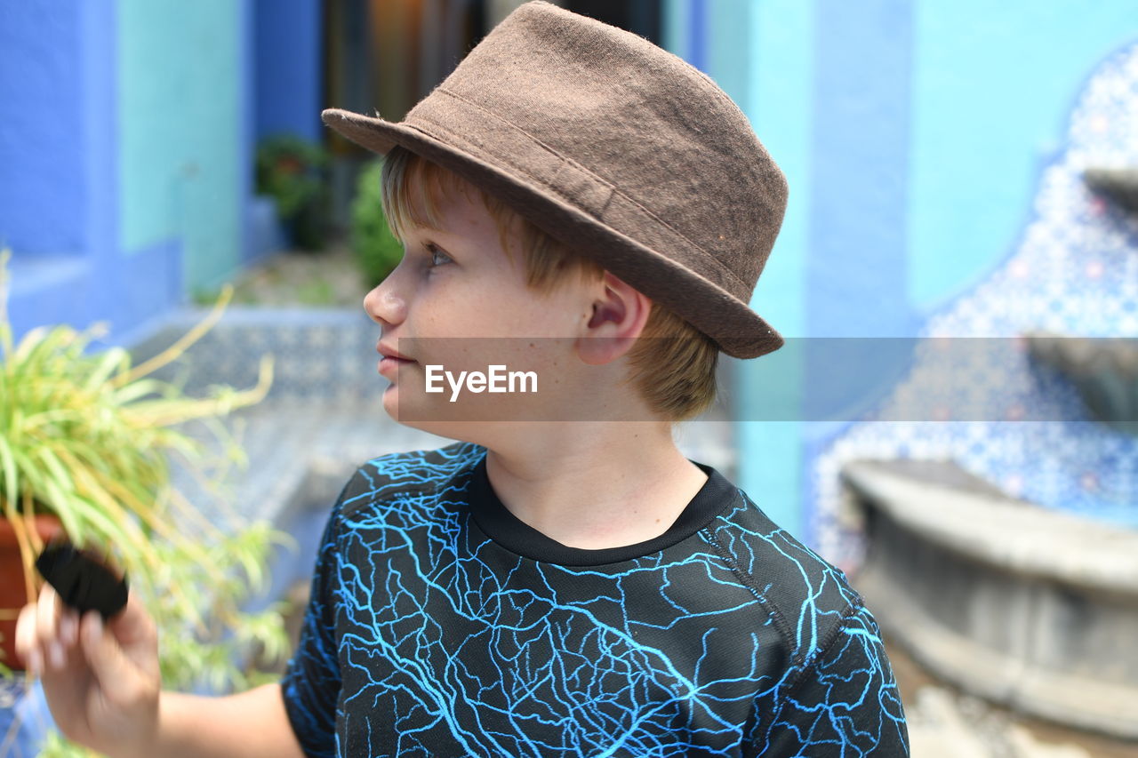 Close-up of boy wearing hat standing outdoors