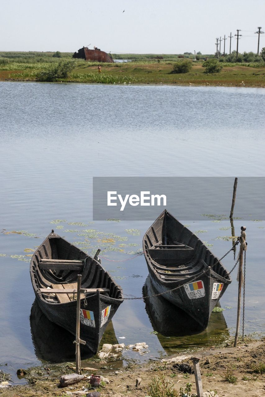 Boat moored on lake against sky