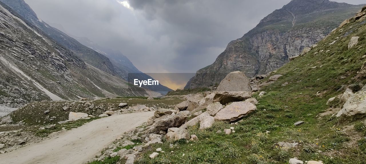 mountain, environment, cloud, scenics - nature, landscape, sky, beauty in nature, nature, mountain range, mountain pass, land, valley, travel, travel destinations, adventure, activity, walking, rock, panoramic, leisure activity, plant, hiking, wilderness, outdoors, overcast, non-urban scene, tourism, fog, ridge, dramatic sky, tranquility, grass, outdoor pursuit, mountain peak, backpacking, wadi, plateau, footpath, tranquil scene, coniferous tree, water, day, road, cloudscape, pinaceae, highland