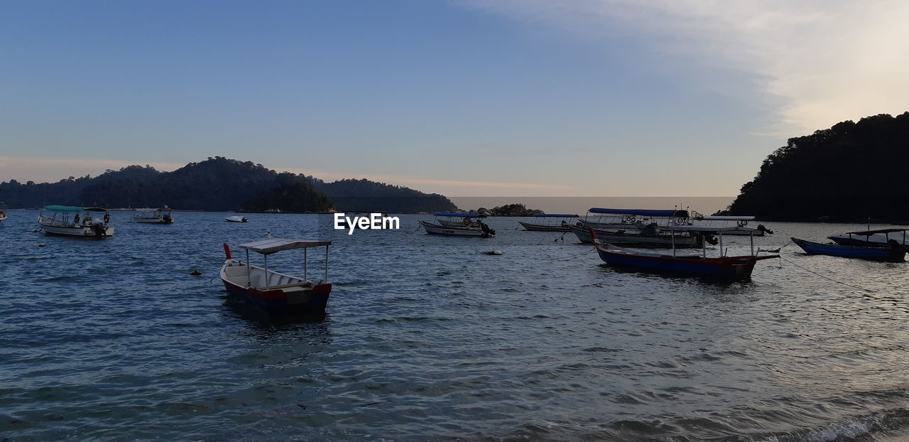 BOATS MOORED IN SEA AGAINST SKY