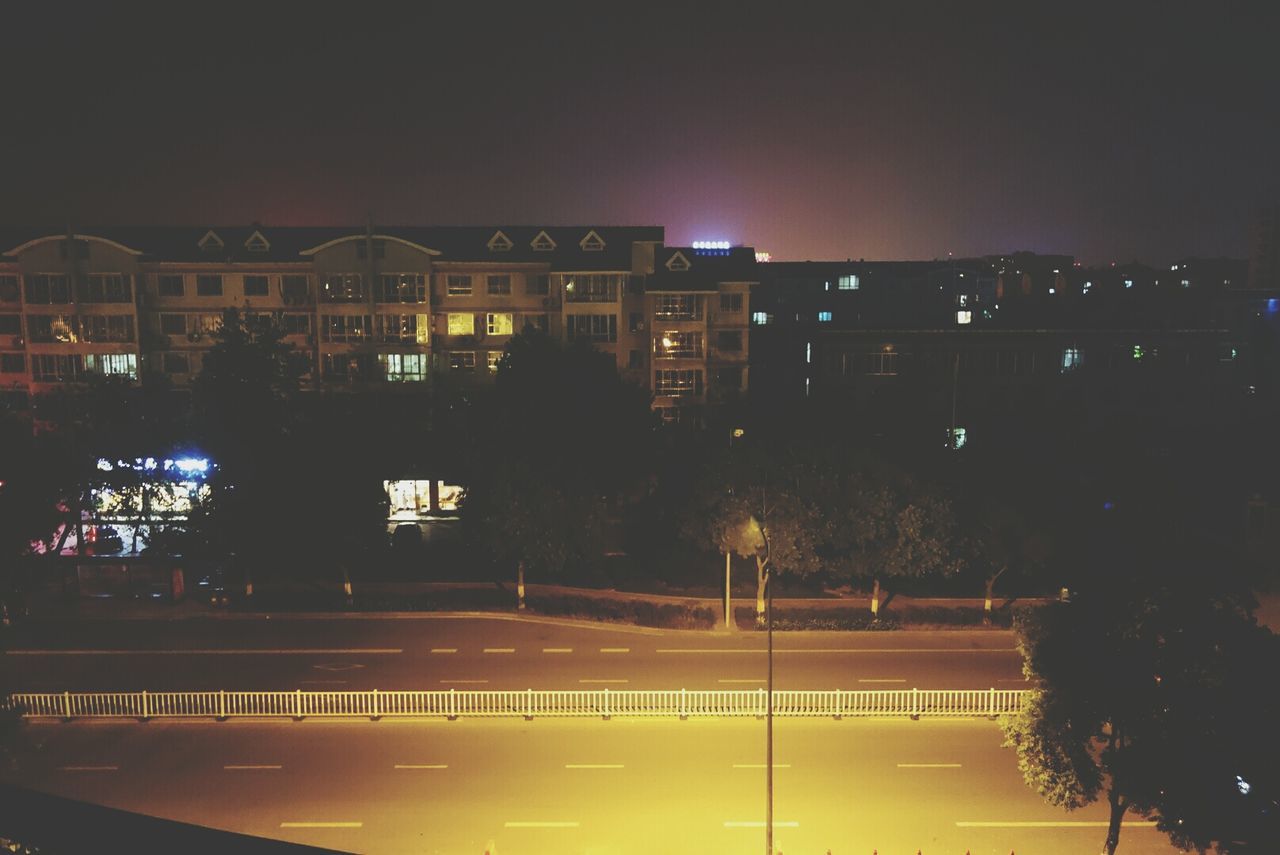 Illuminated city street against buildings at night