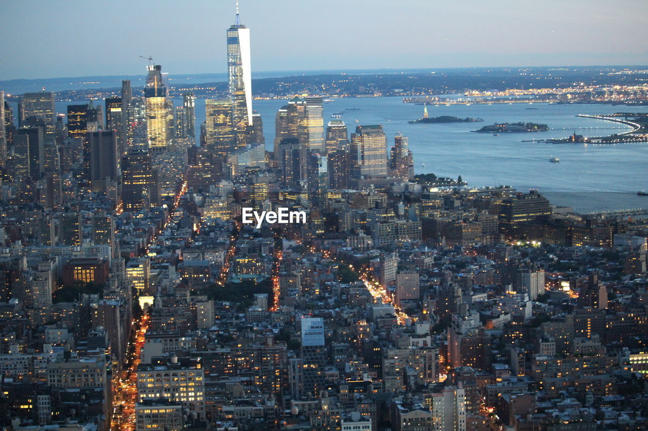 Aerial view of illuminated city by sea