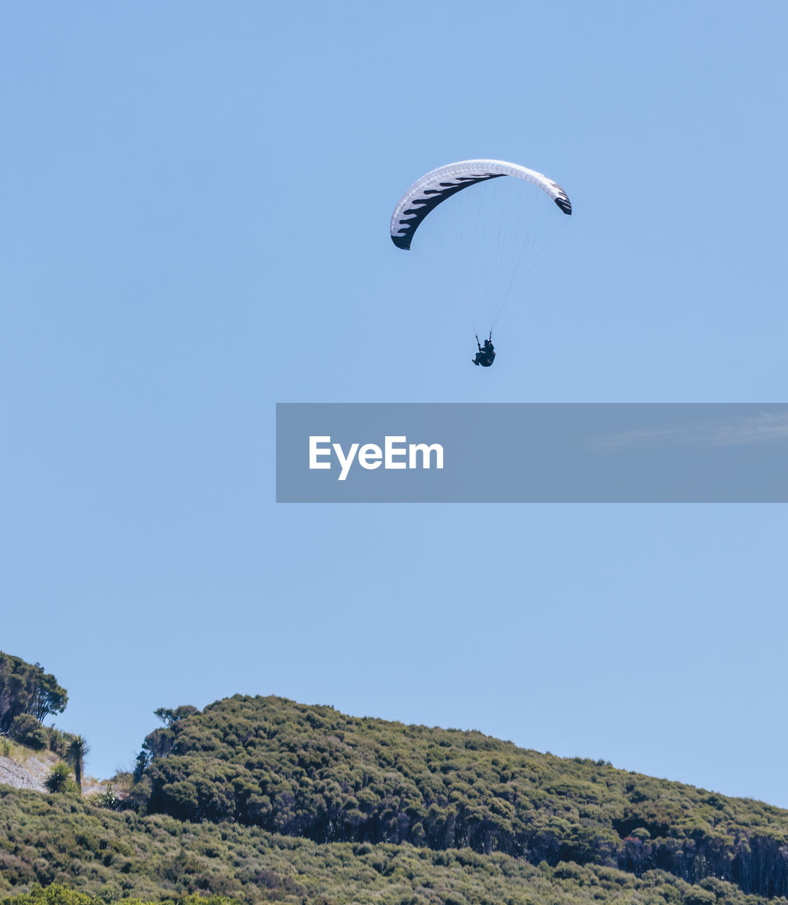 Low angle view of person paragliding against clear sky