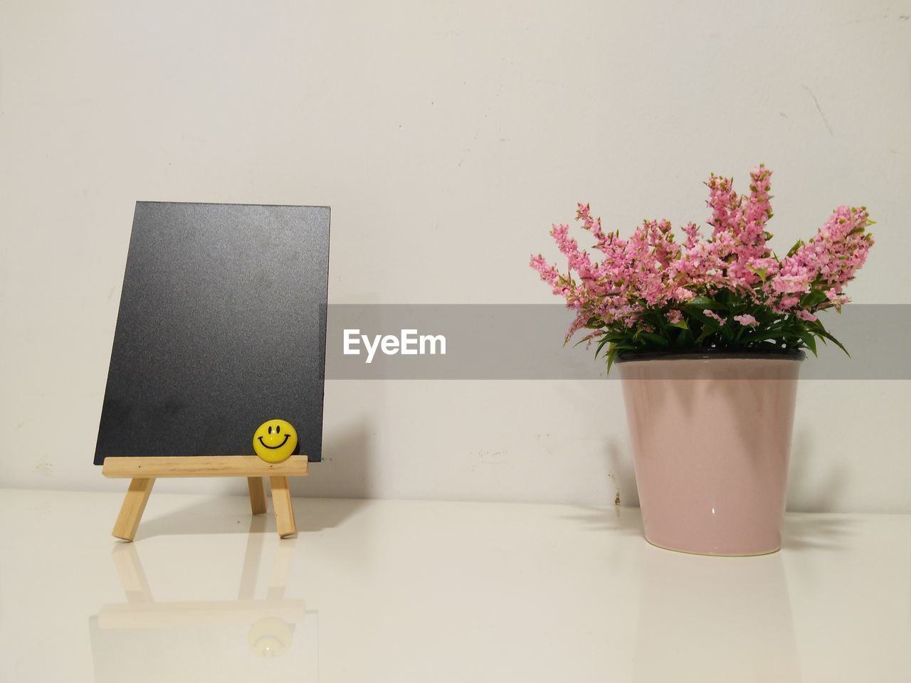 Flower vase by blackboard on table at home