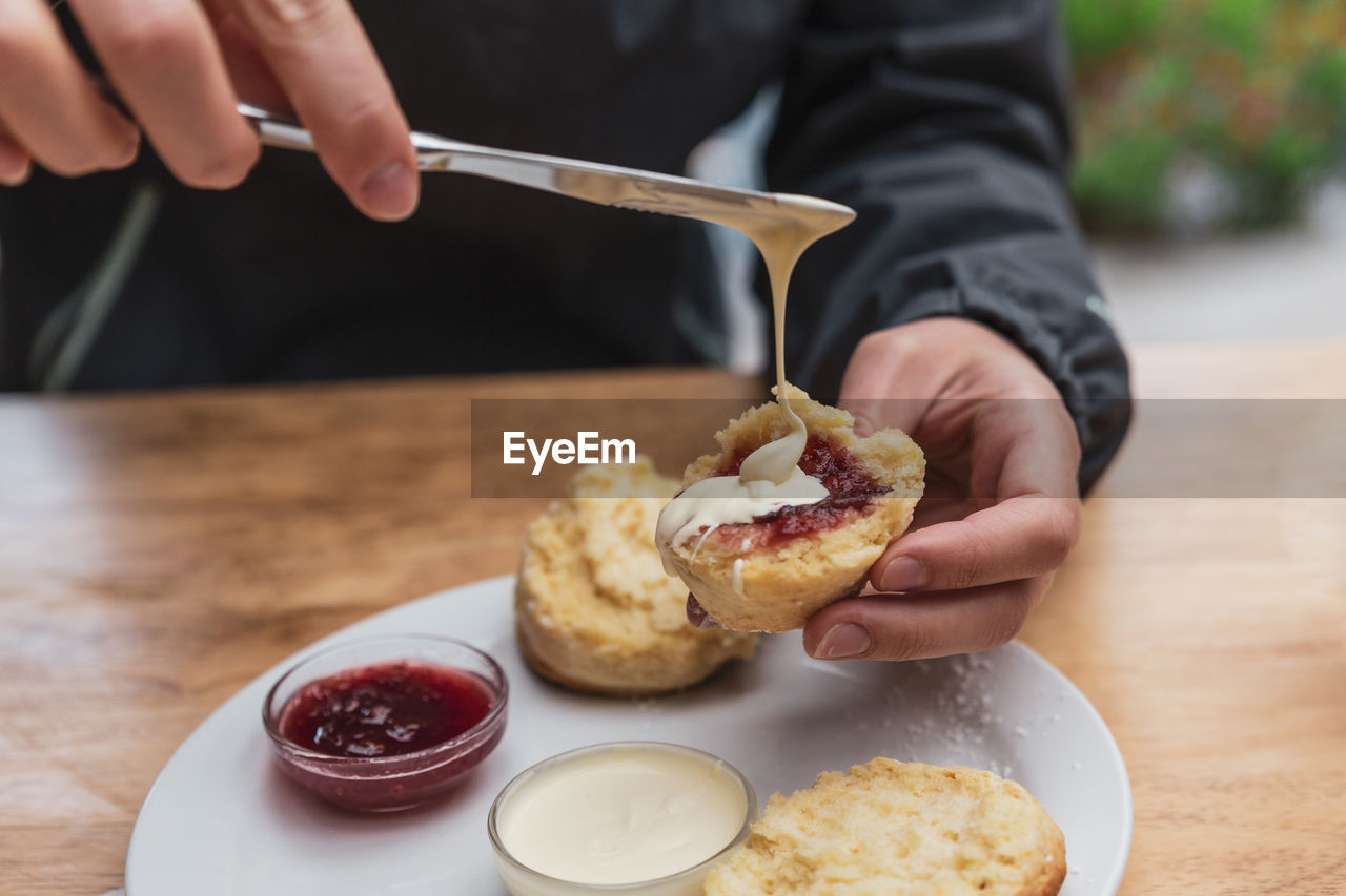 Cropped hands of person having breakfast on table