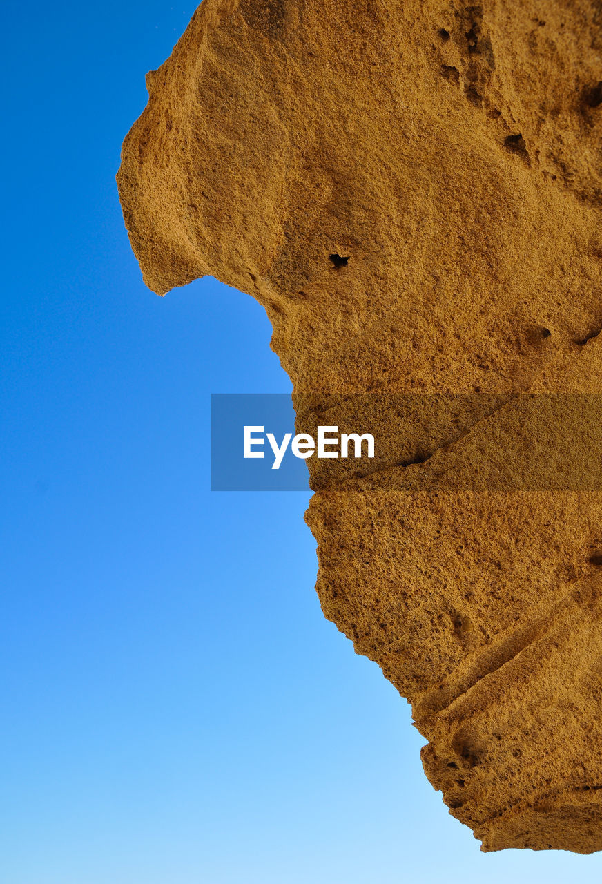 Low angle view of rock formation against clear blue sky