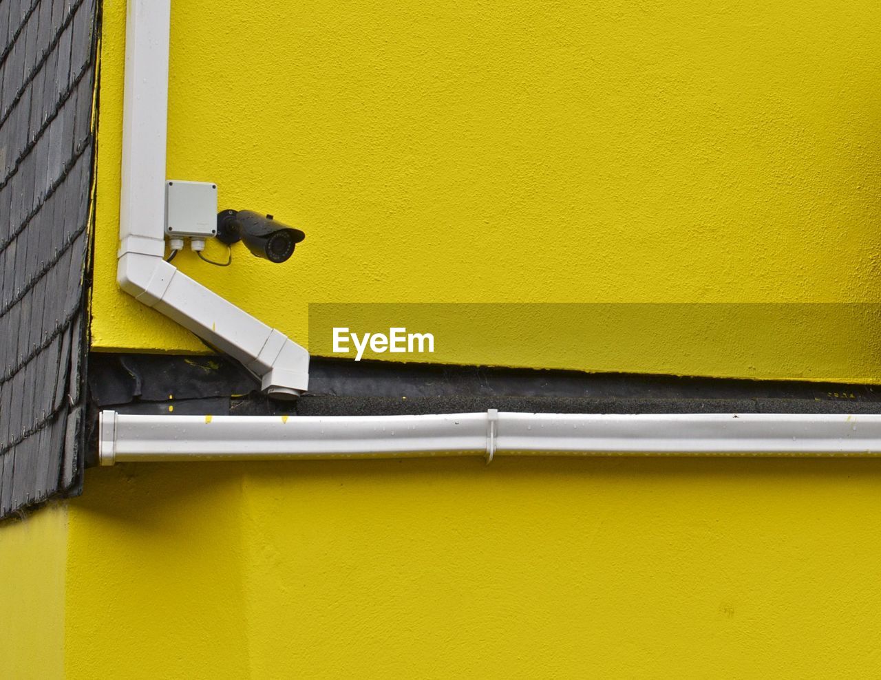 Low angle view of security camera on yellow wall