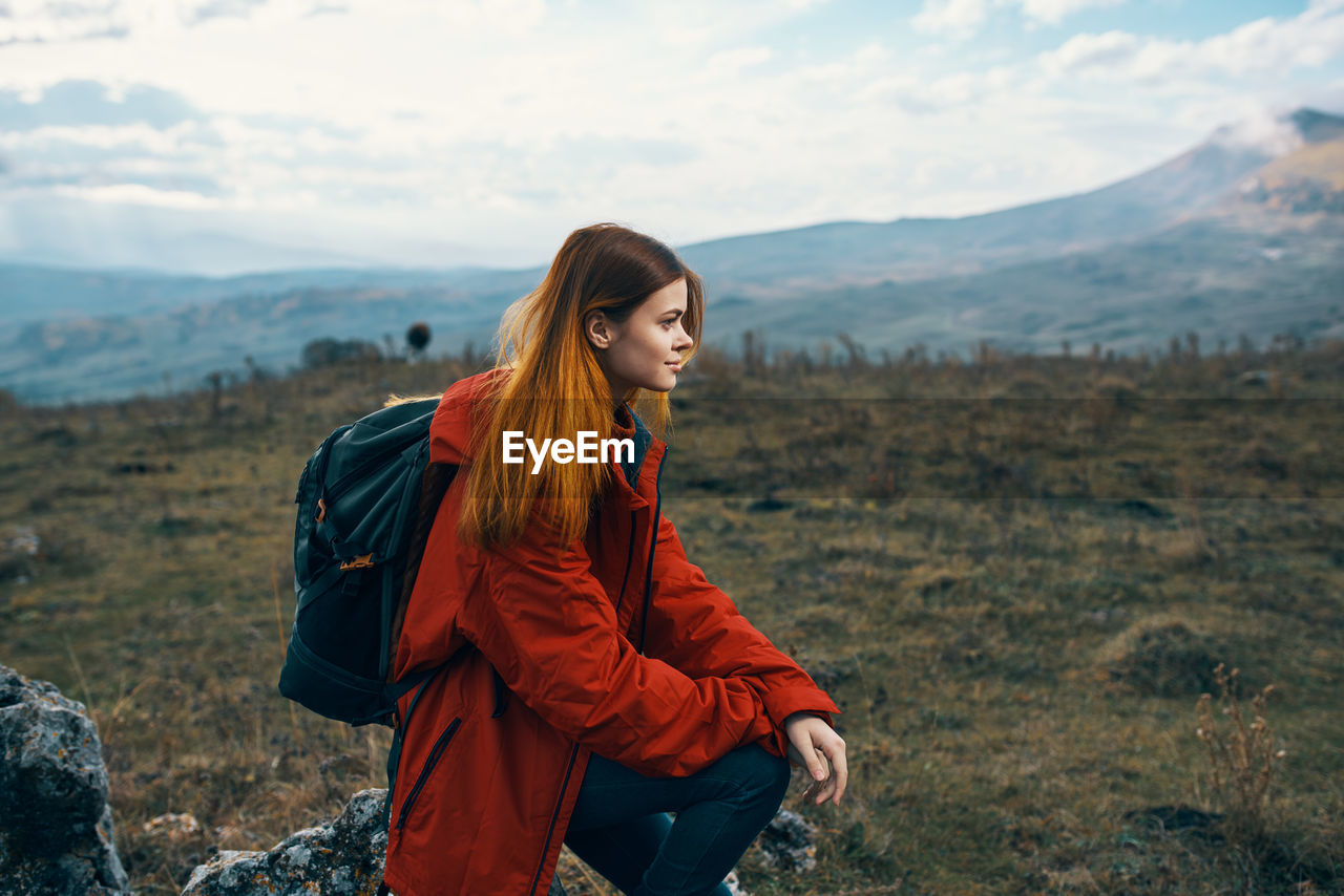 Young woman standing on land against sky