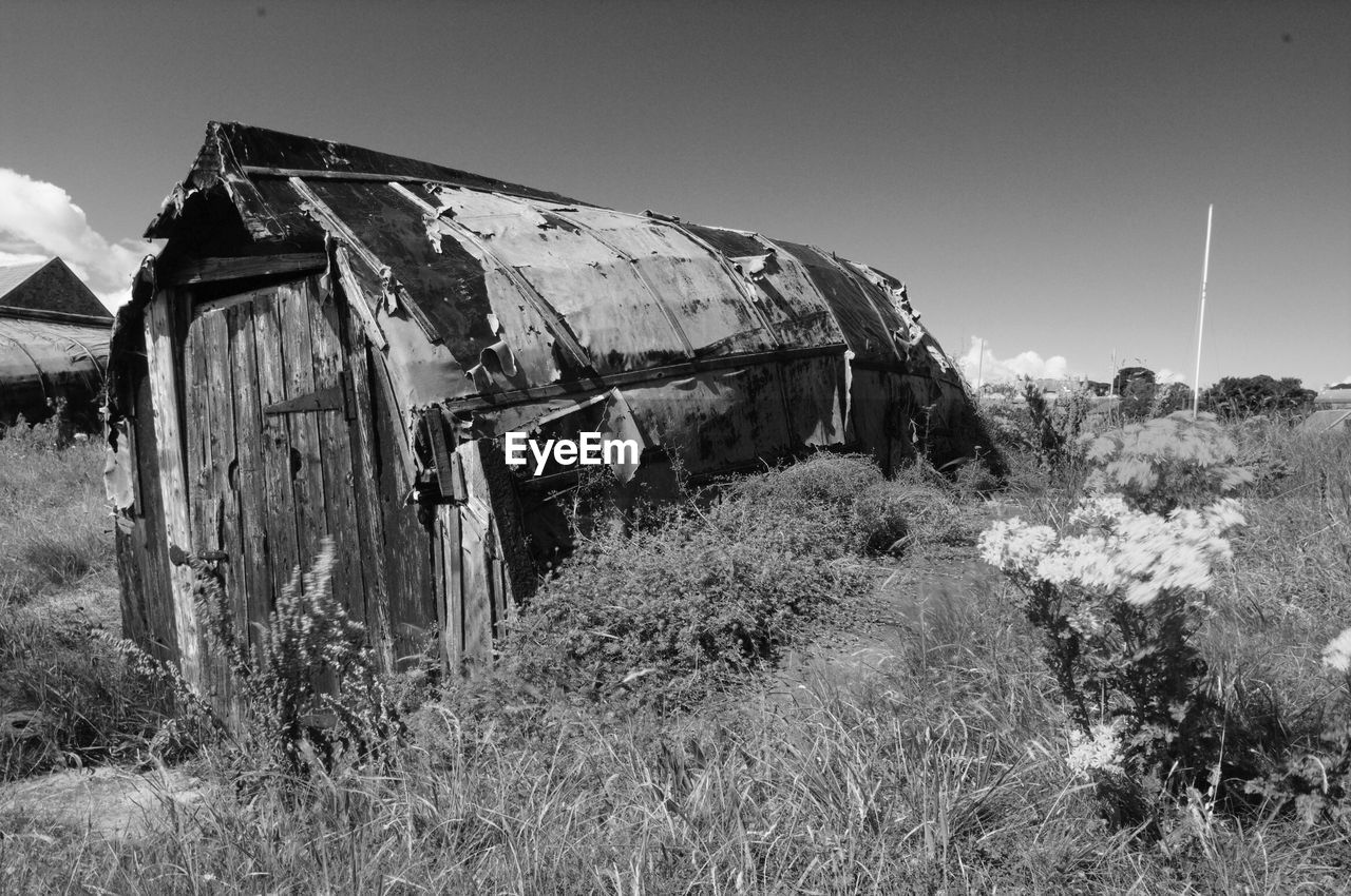 Abandoned damaged house on field against sky