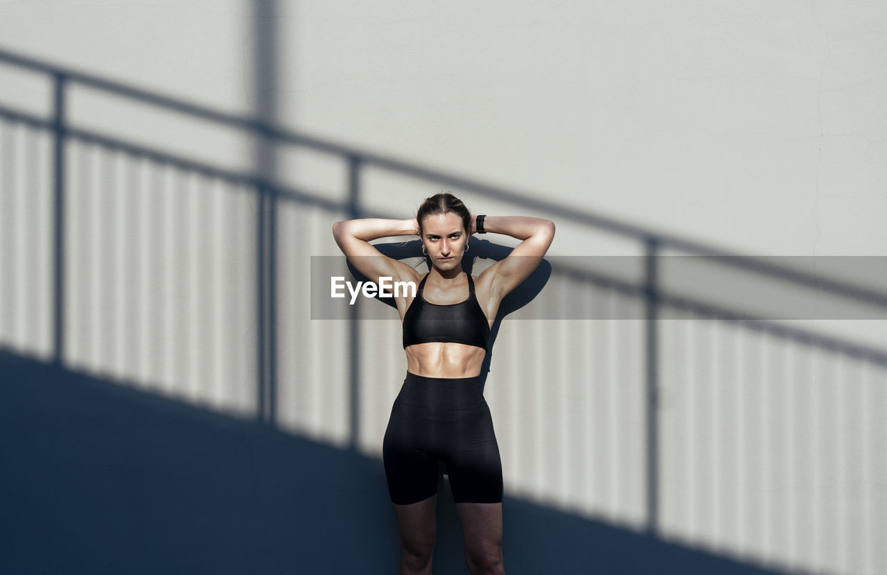 Young athlete with hands behind back standing in front of gray wall