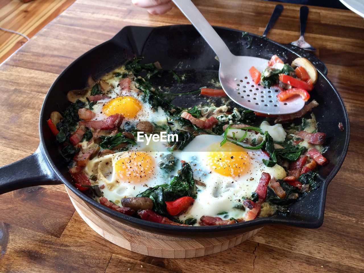 Fried eggs with vegetables in pan