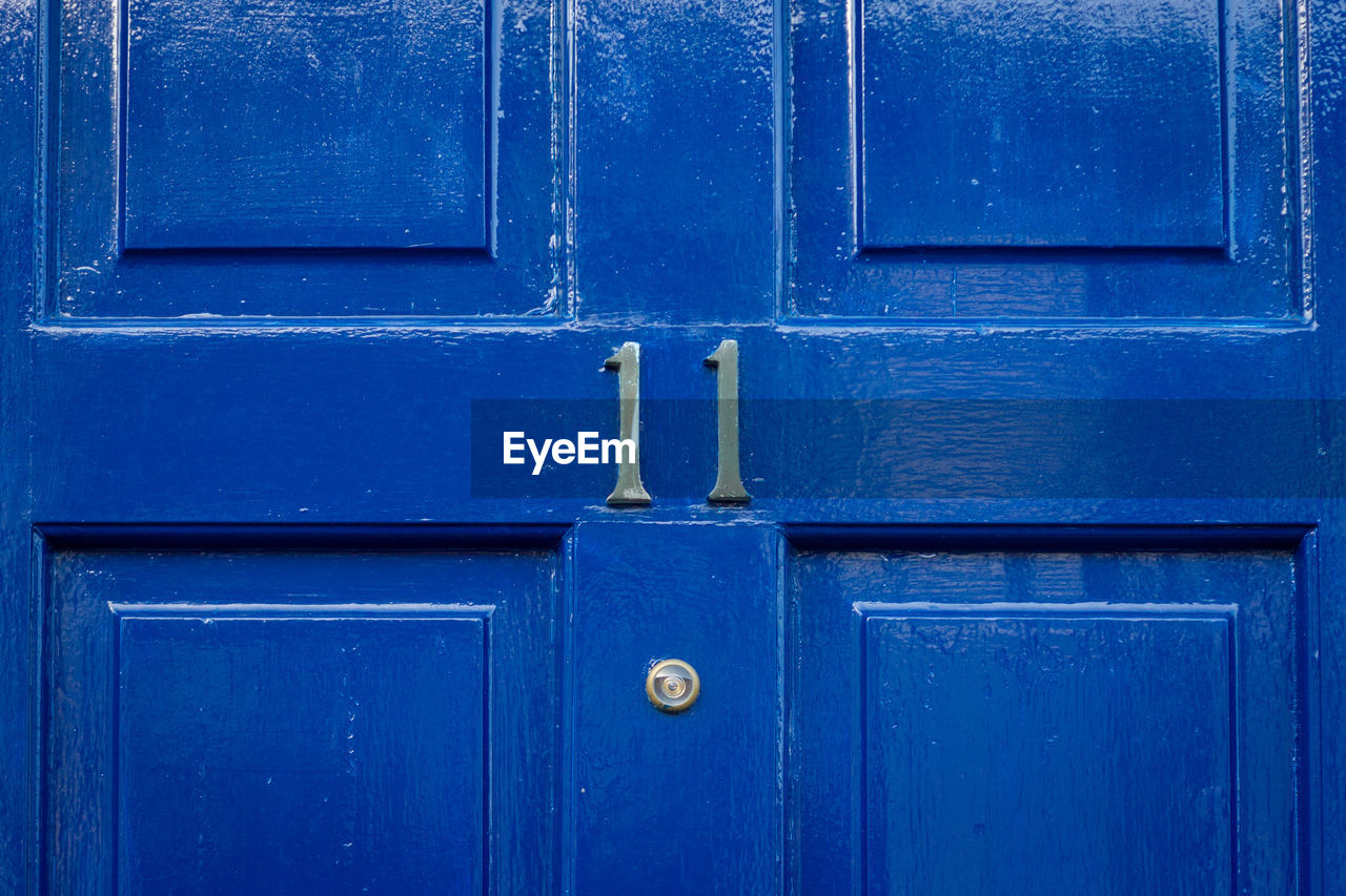 House number 11 on a blue wooden front door in london 