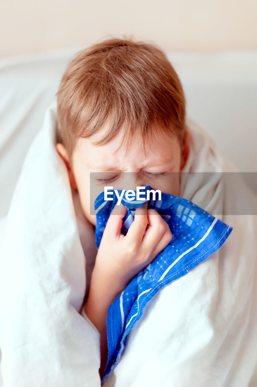 Sick child with thermometer. boy with a runny nose. 1boy blows his nose in a handkerchief