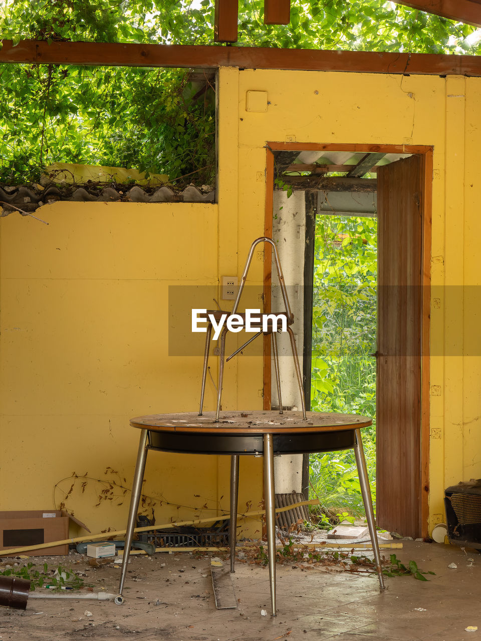 Chair over an old table in an abandoned room full of dirt.