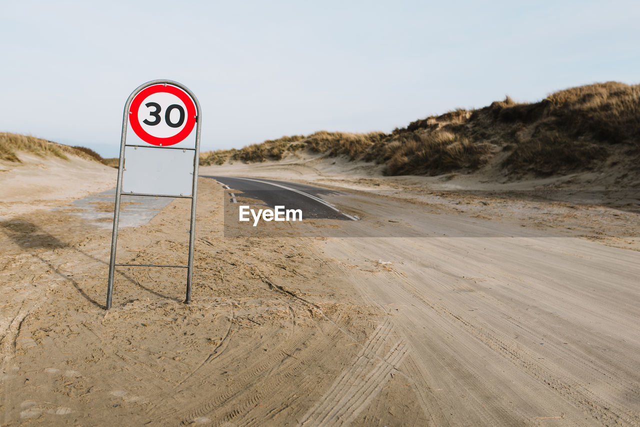 Road sign on field against clear sky