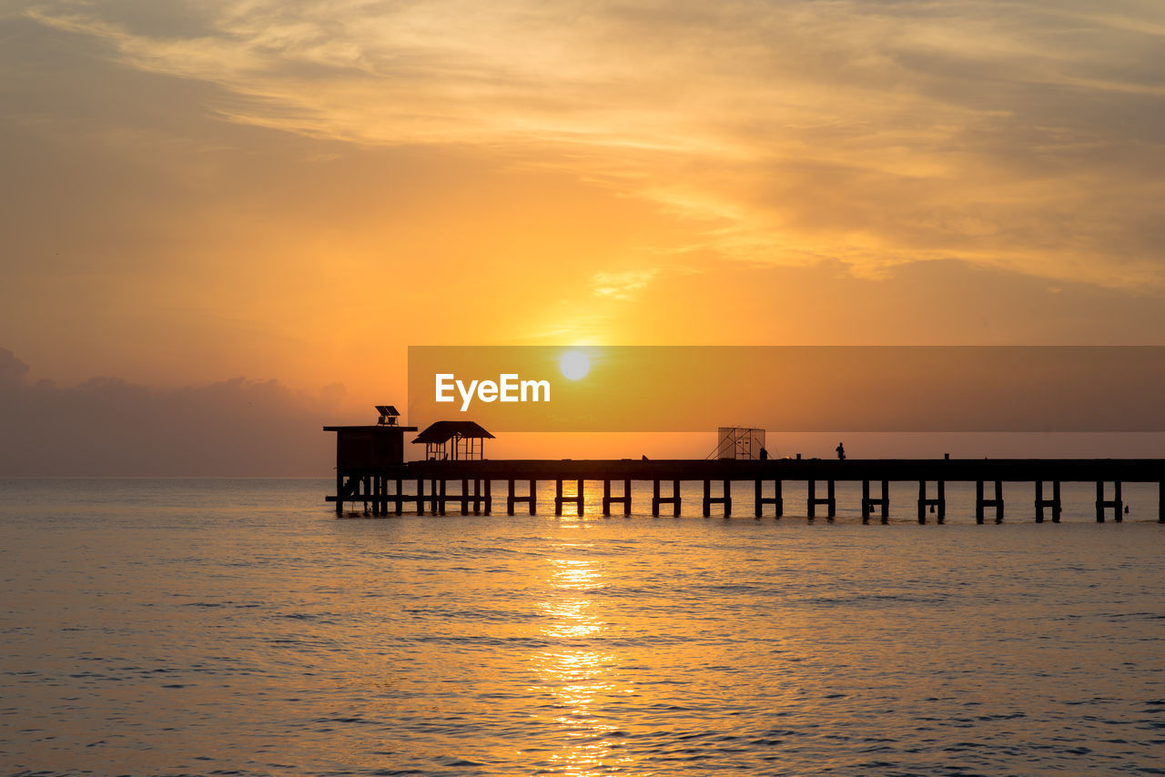 Silhouette pier over sea against sky during sunset