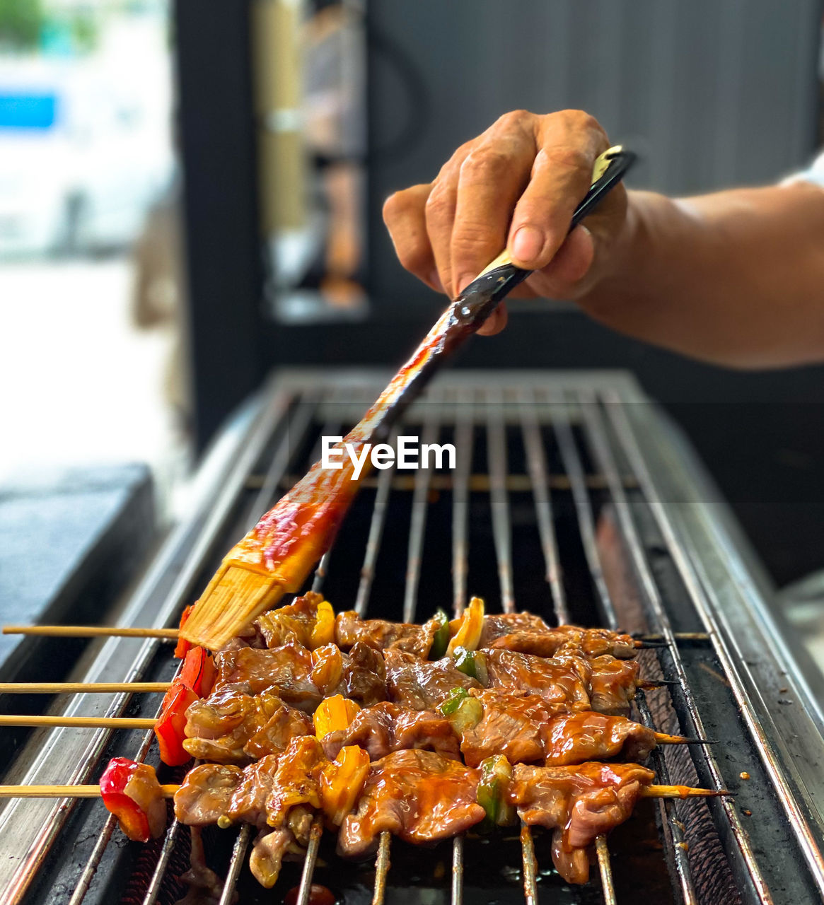 Cropped image of person preparing food on barbecue grill