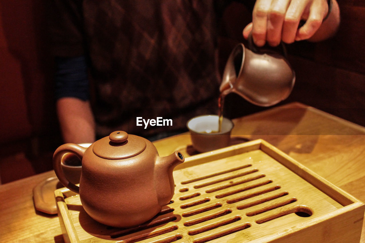 MIDSECTION OF MAN POURING TEA CUP