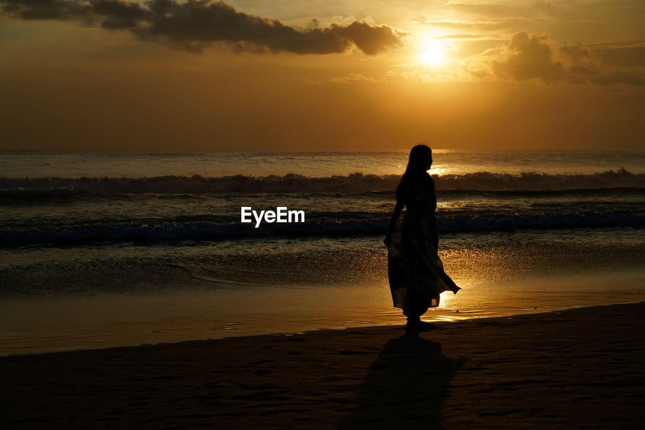 Silhouette woman on beach during sunset