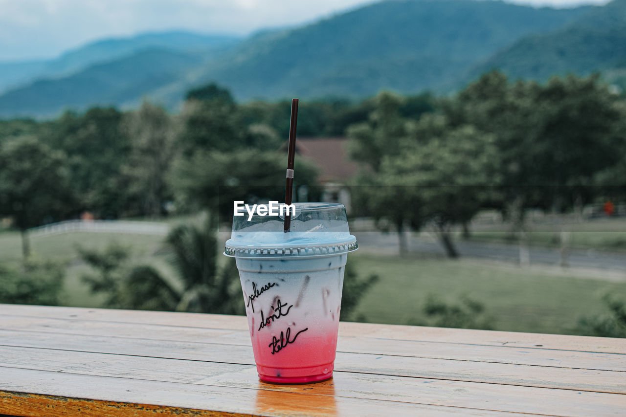 CLOSE-UP OF DRINK SERVED ON TABLE AGAINST MOUNTAIN