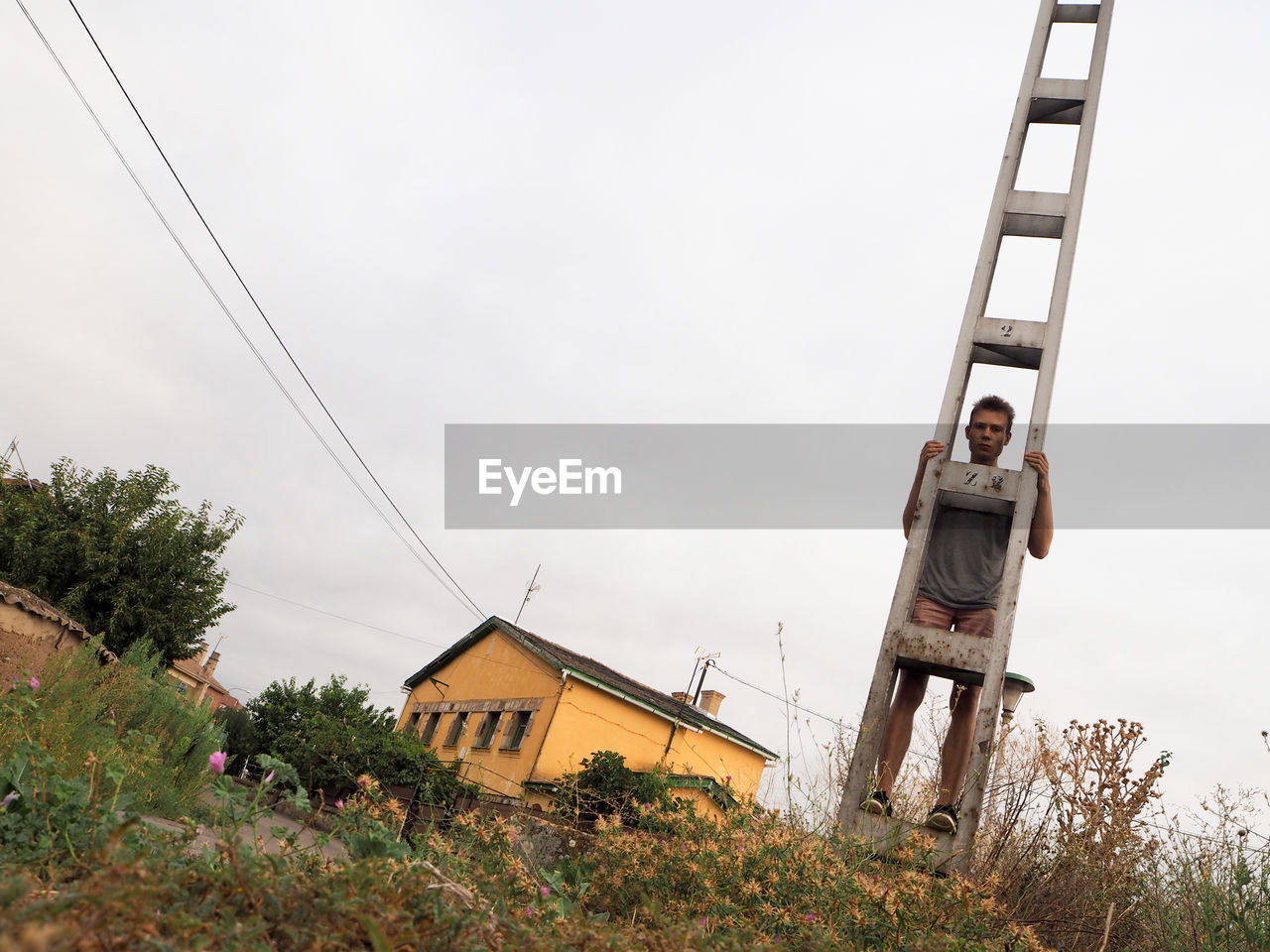 Low angle view of man standing on electricity pole