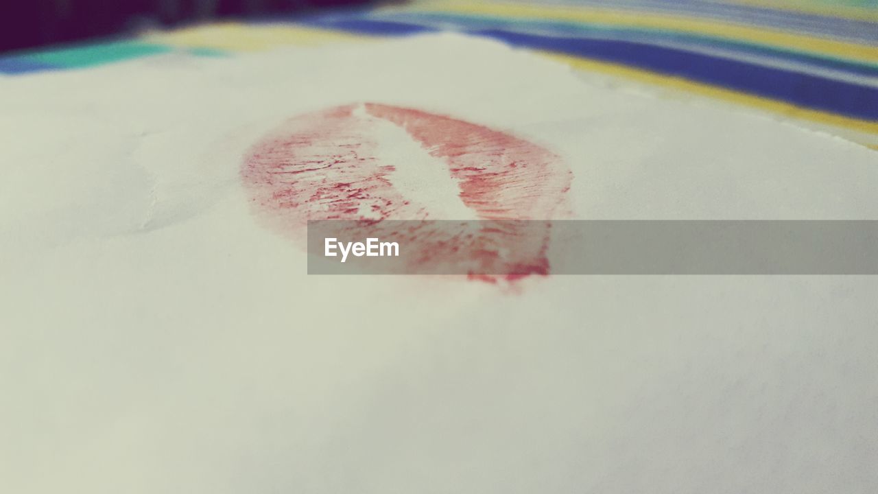 Close-up of red lipstick stain on white handkerchief at home