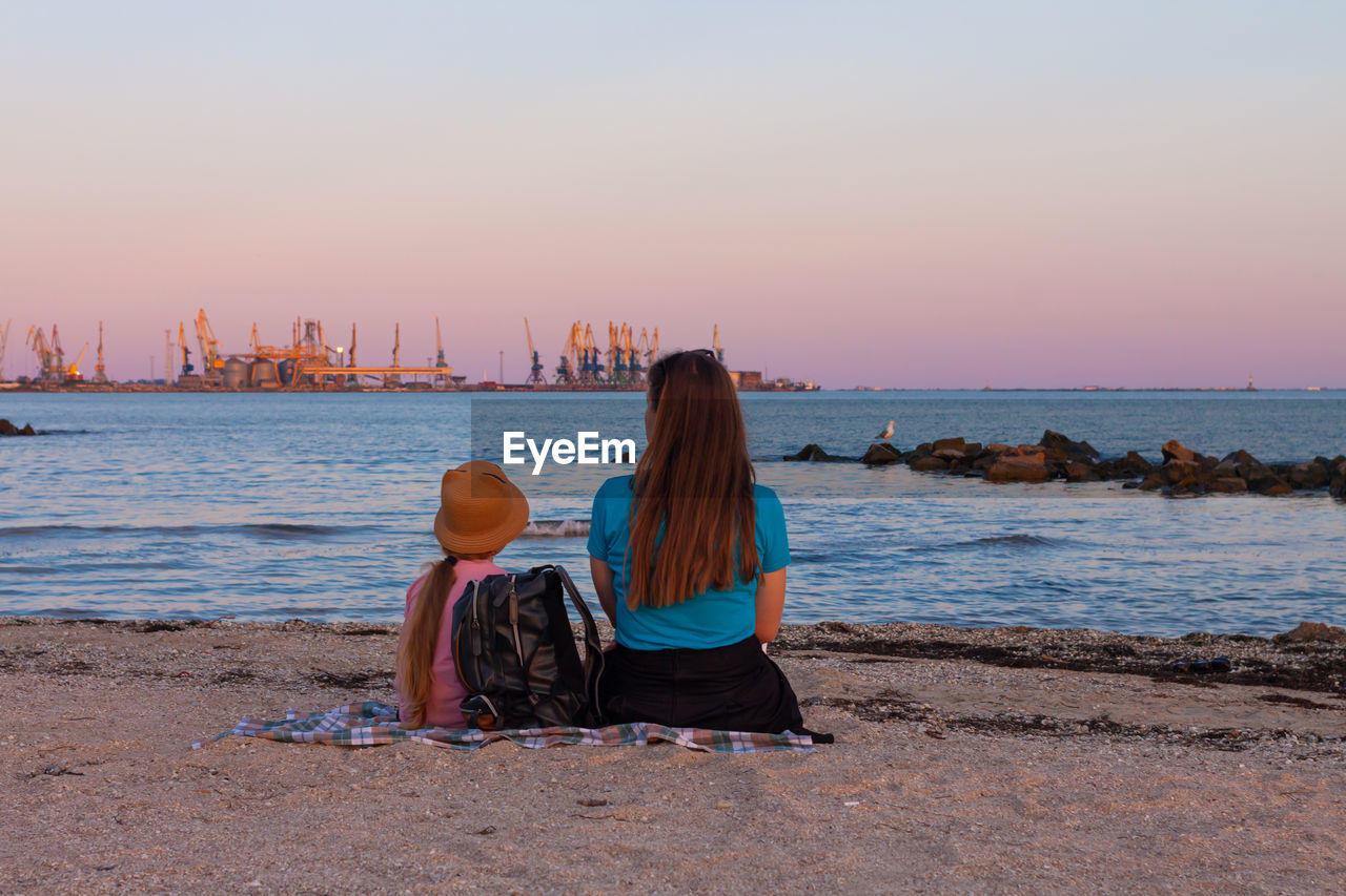 Girl staycation picnicking on sea beach  amazing colorful sunset.trend local travel.evening seascape