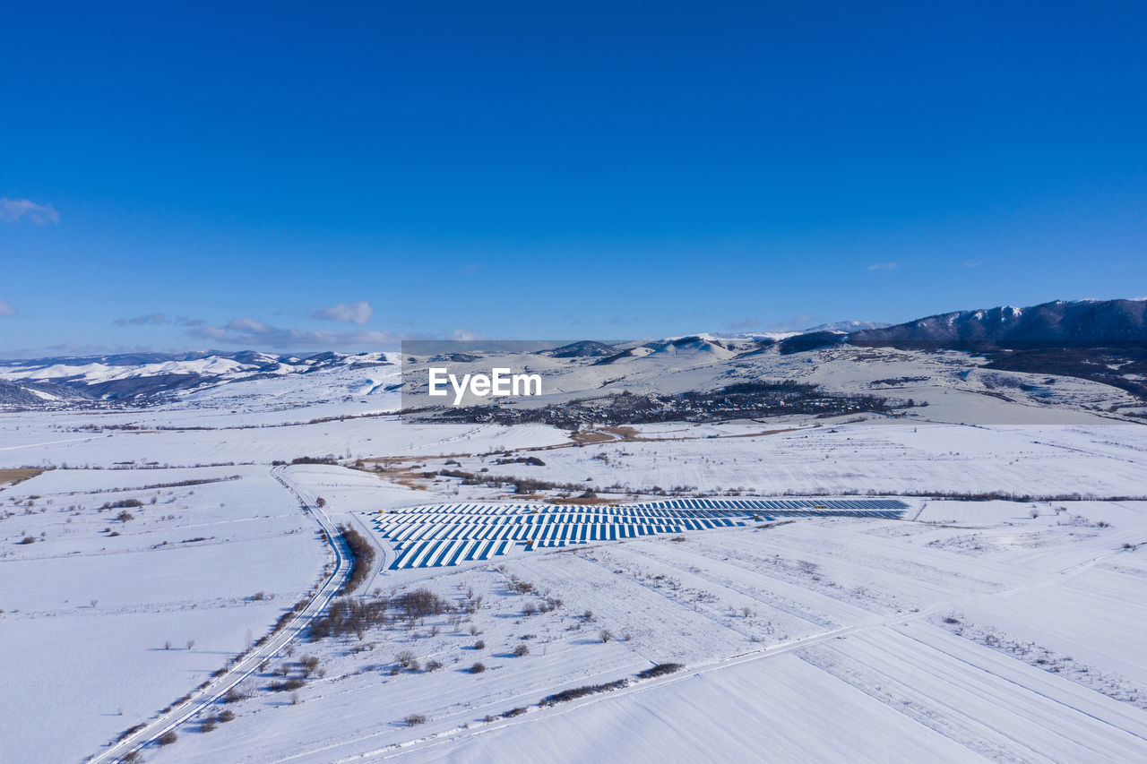 Aerial drone view of snow covered solar panel park, photovoltaic power station in the winter