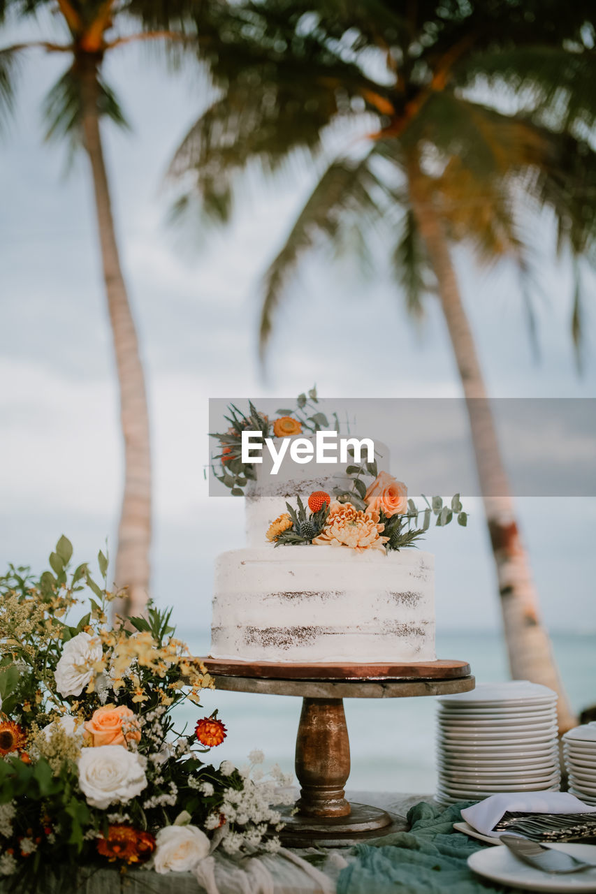 Cake on table against palm trees