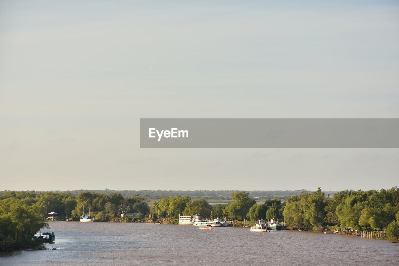 BOAT SAILING IN RIVER AGAINST SKY