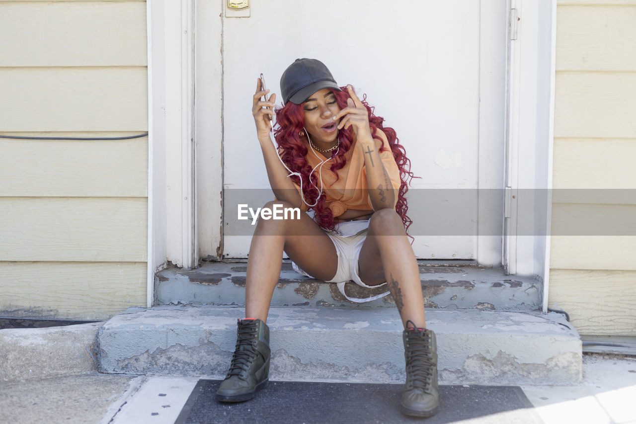 Young woman listening to music at her front door