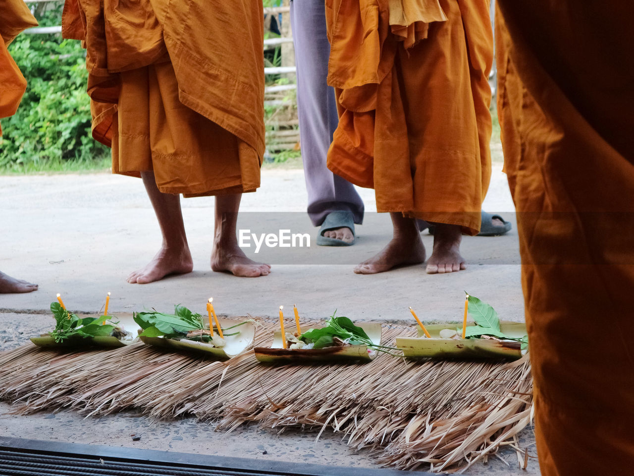 Low section of monks standing by religious offerings on walkway