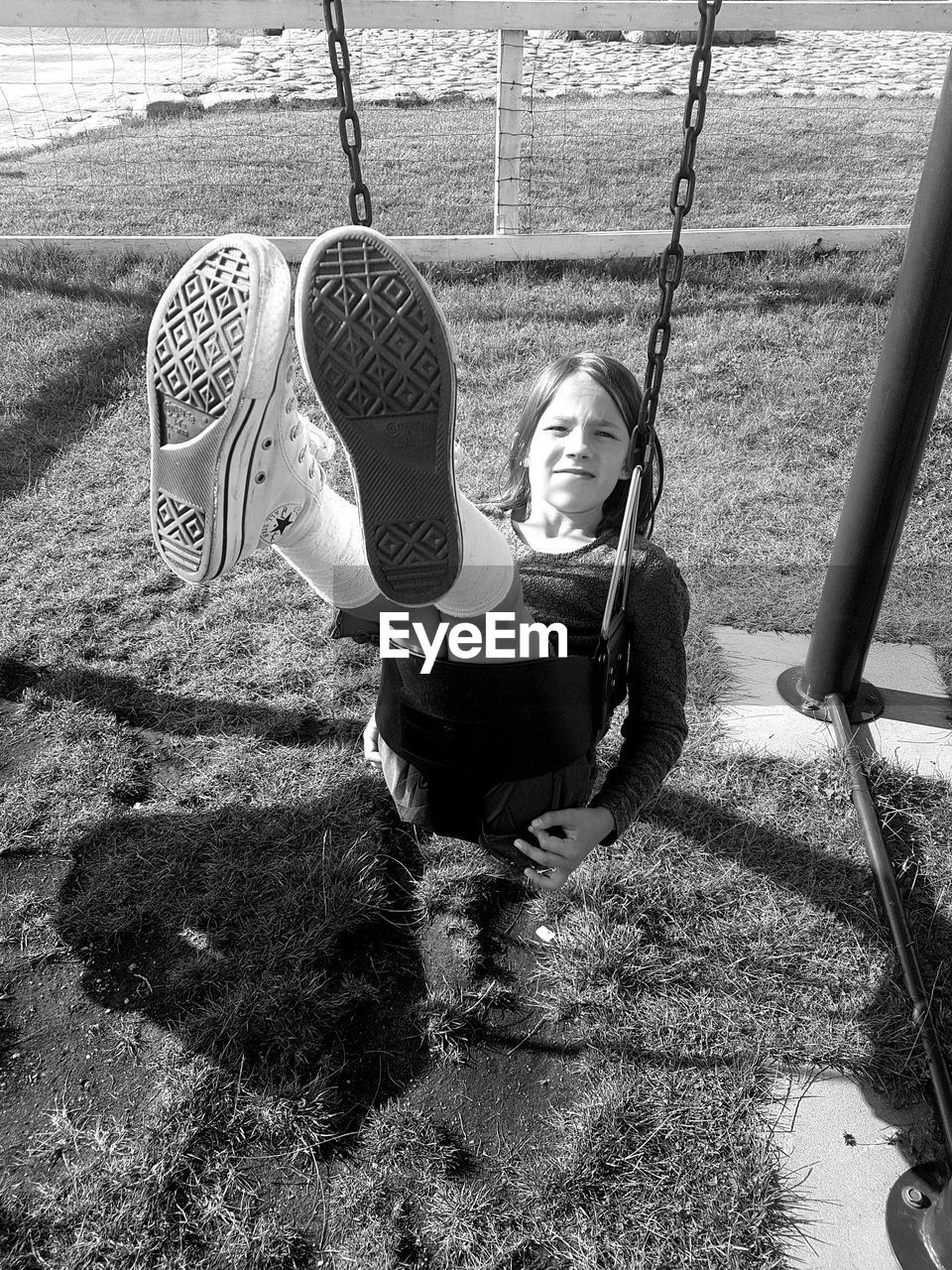 Full length portrait of girl on swing in playground